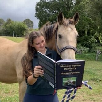 Girl and buckskin horse reading Modern Equine Dentistry together.